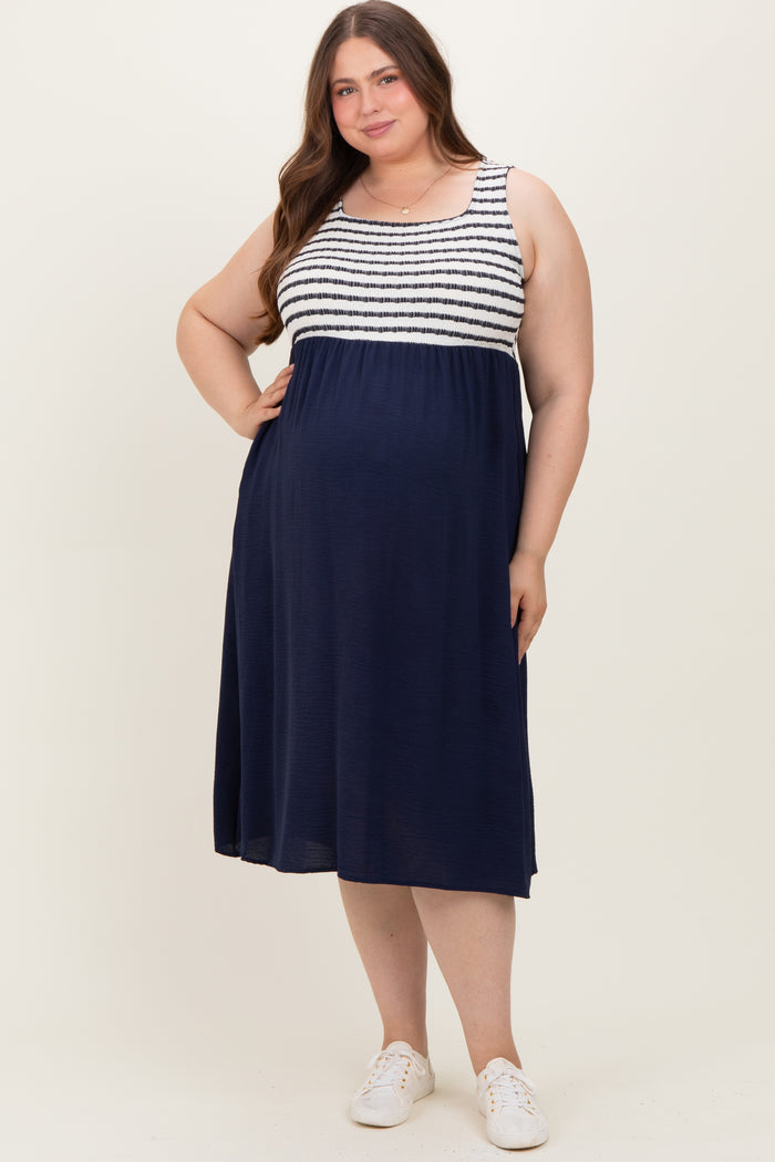 woman wearing a navy maternity dress with a striped top and a flowy skirt, showing off a baby bump