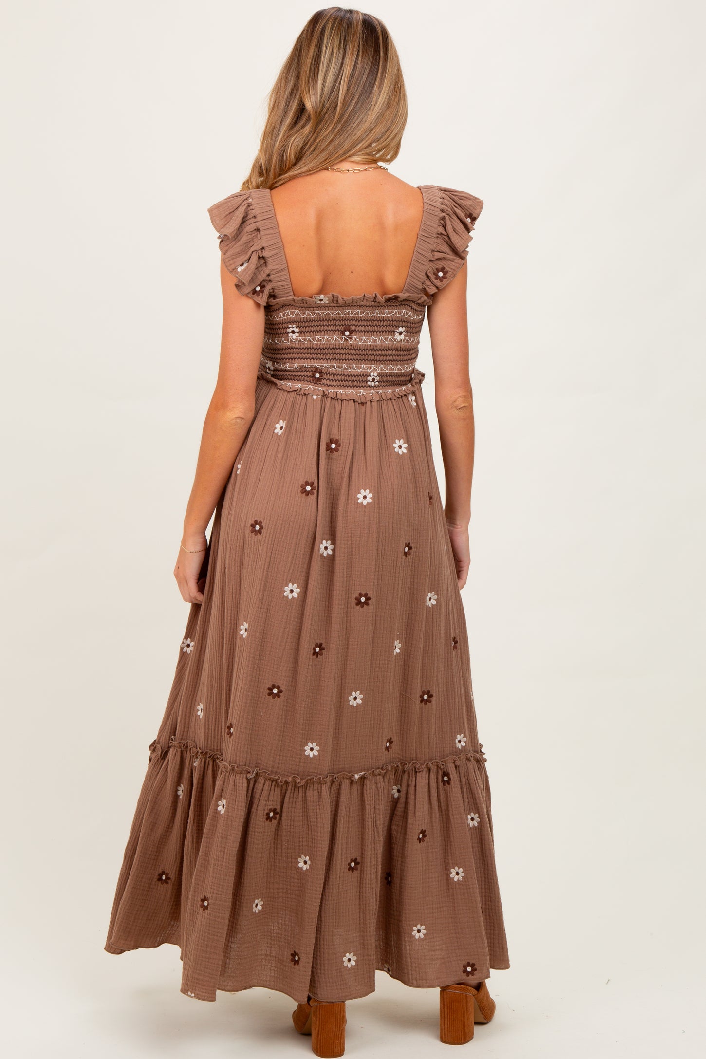 woman wearing a brown floral print maternity maxi dress with ruffled sleeves and a smocked bodice, showing her baby bump