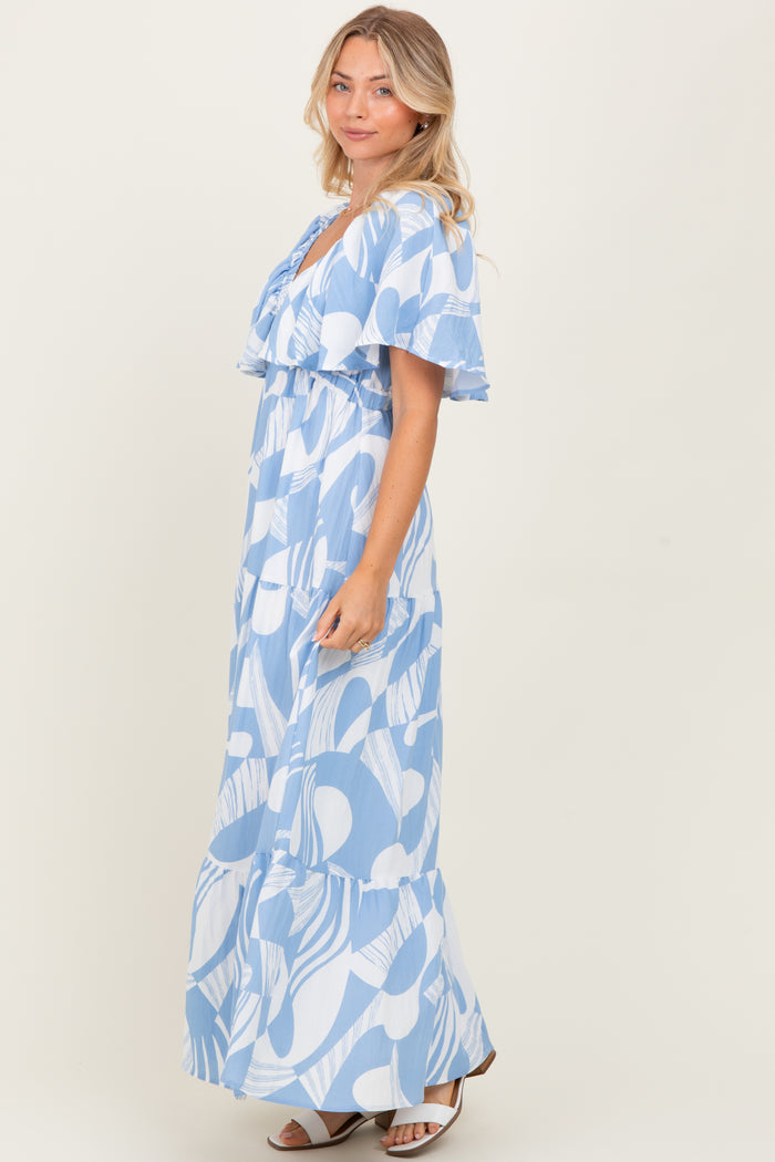woman wearing a blue and white patterned maxi dress with flutter sleeves and a tiered skirt
