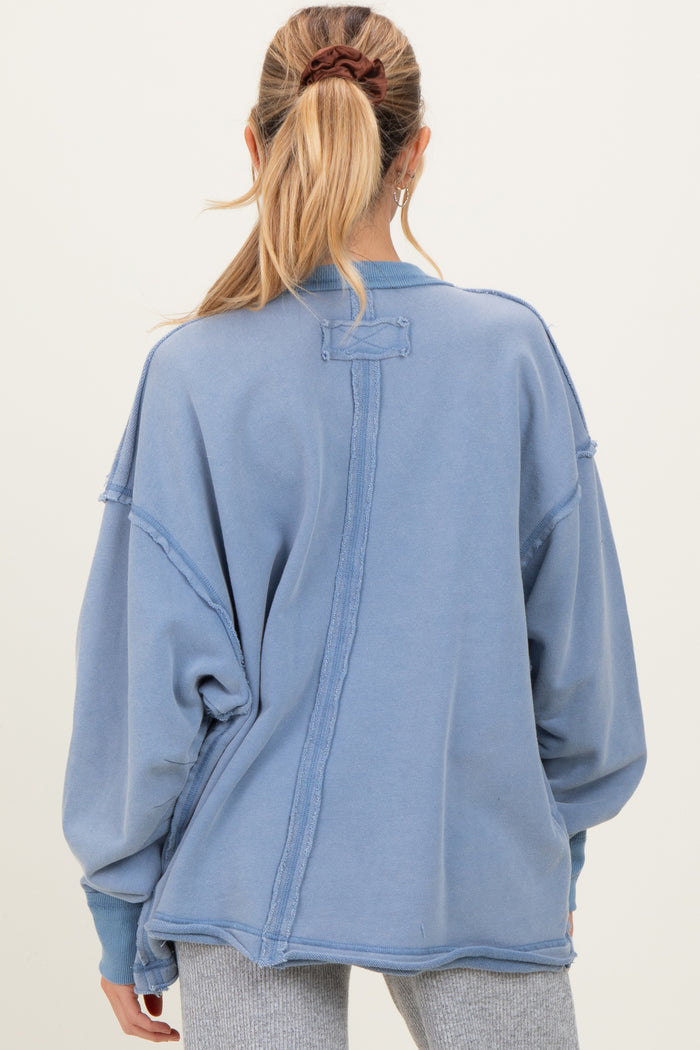 woman wearing a blue oversized maternity sweatshirt with a relaxed fit and crew neckline, viewed from the back