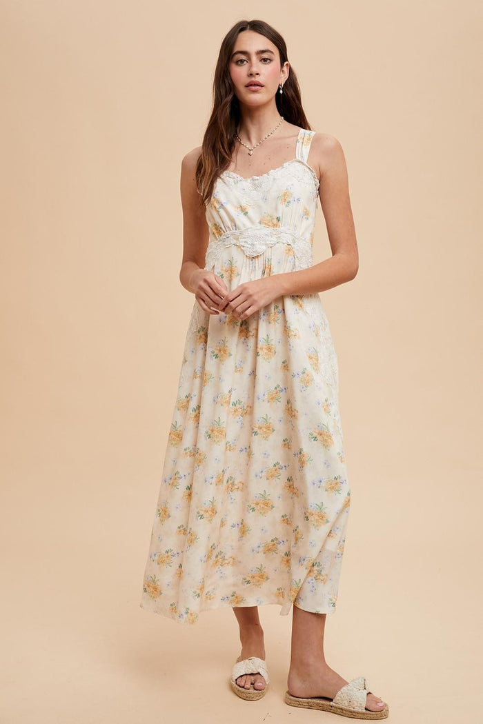 woman wearing a cream floral maxi dress with adjustable straps and a gathered waist, styled with sandals