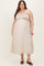 woman wearing a light floral maternity plus dress with adjustable straps, showcasing her baby bump