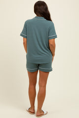 woman wearing a green maternity pajama set with shorts and a short-sleeve top, seen from the back
