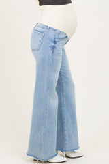 woman wearing light blue maternity flared jeans with a white over-the-bump waistband and visible baby bump