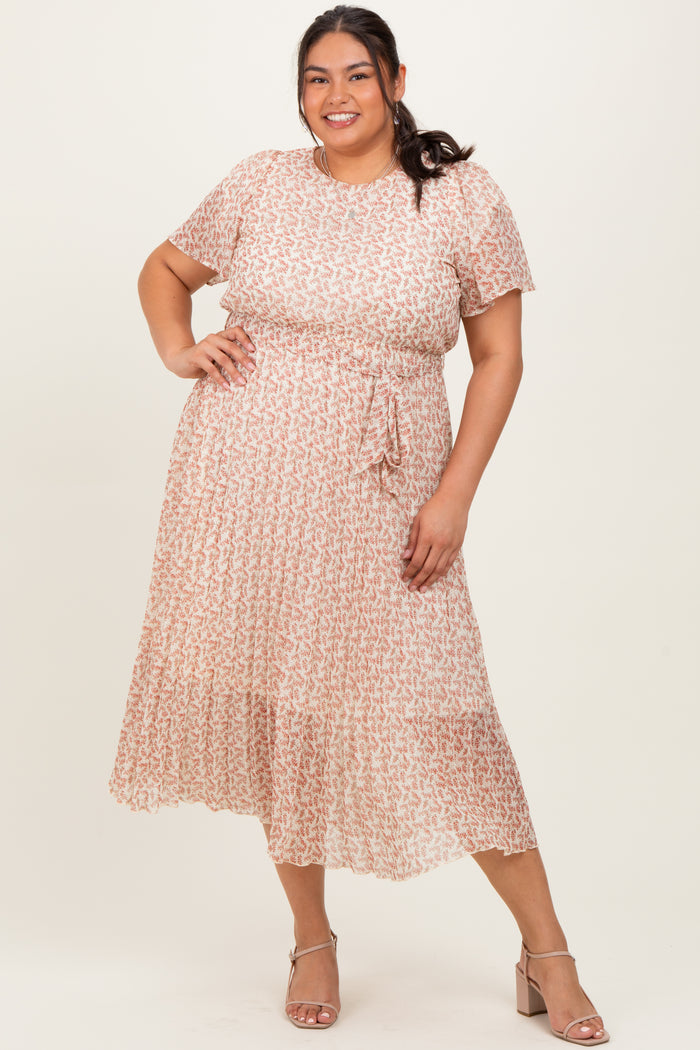 woman wearing a pink and white patterned plus size midi dress with short sleeves and a tie waist detail