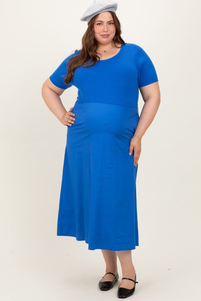 woman wearing a bright blue short sleeve maternity dress with a fitted bodice and a flowing skirt, displaying her baby bump