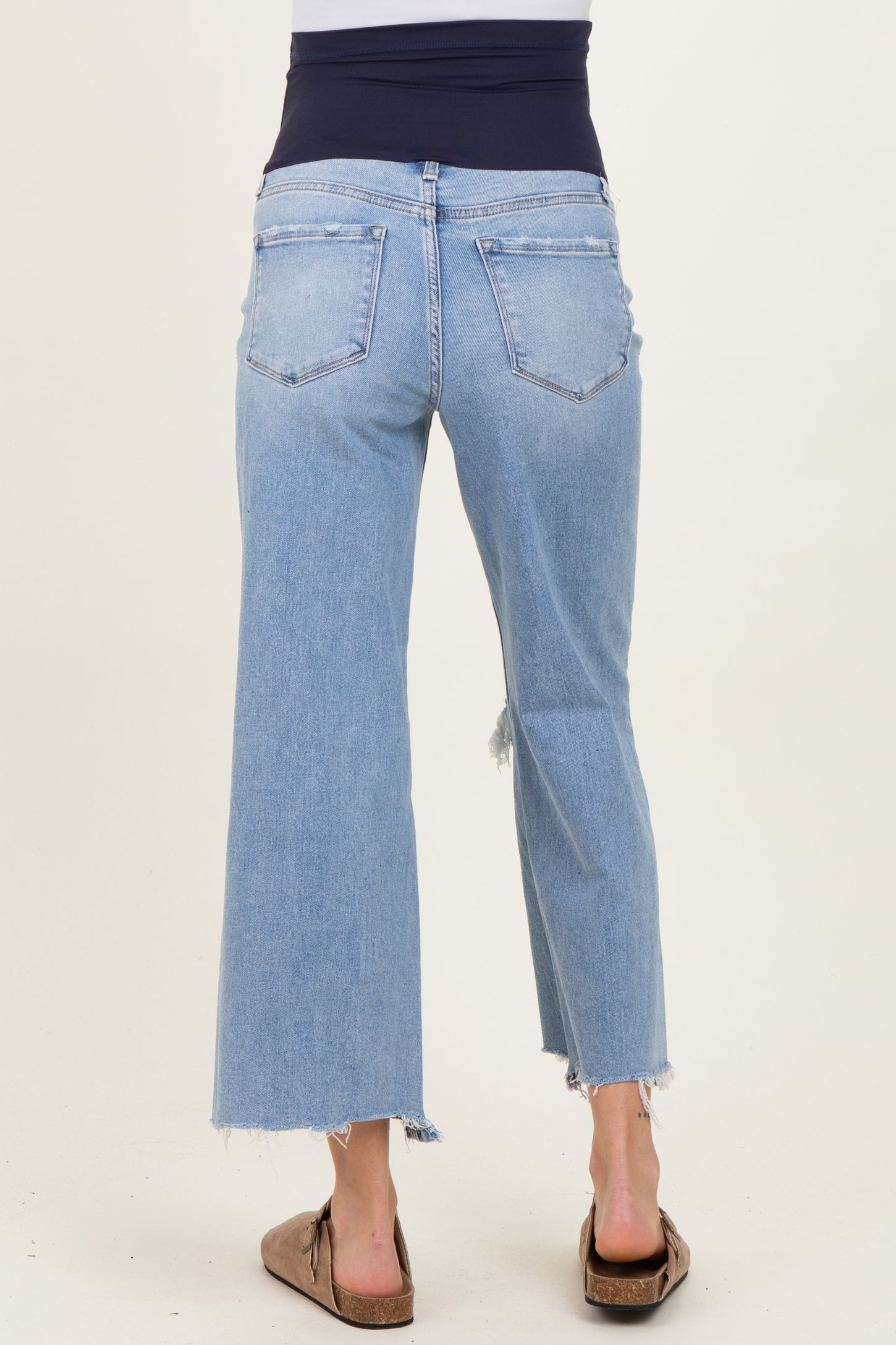 maternity wear light blue high-waisted cropped jeans with a distressed hem, worn by a model showing a baby bump