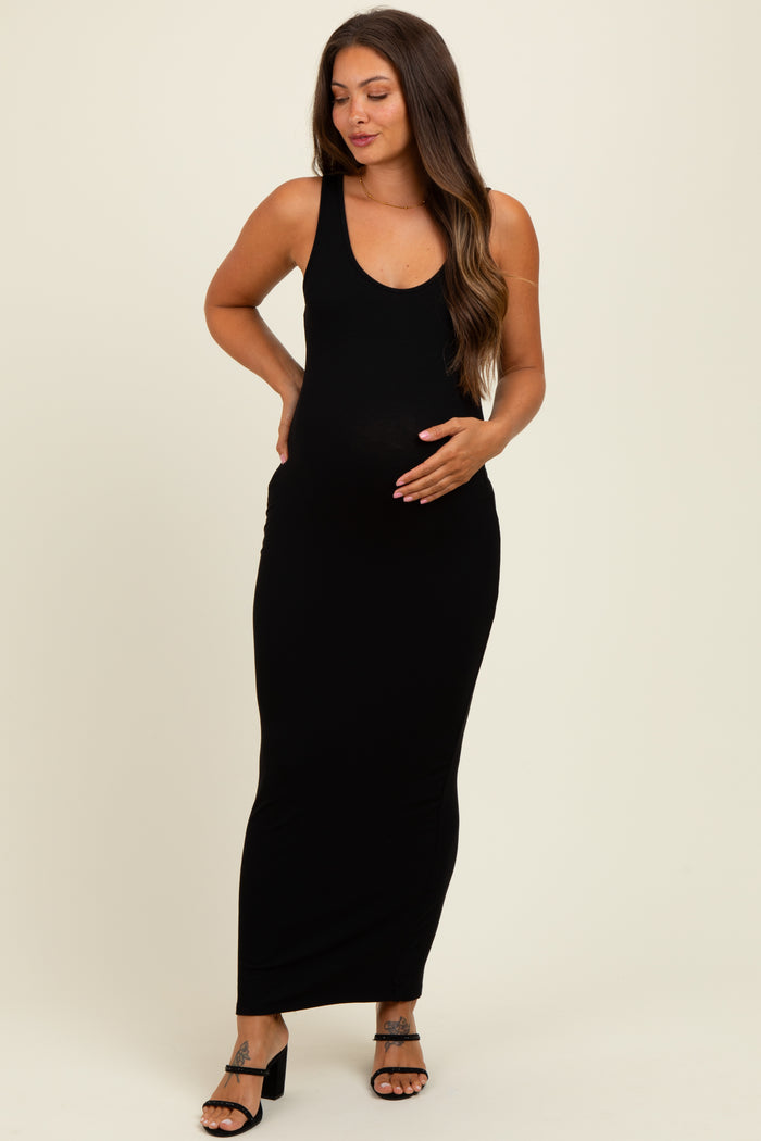 woman wearing a black ribbed maternity maxi dress and holding her baby bump
