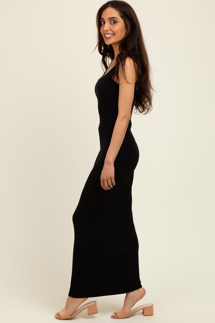 woman wearing a black sleeveless maxi dress and nude block-heeled sandals, posed sideways with a smile