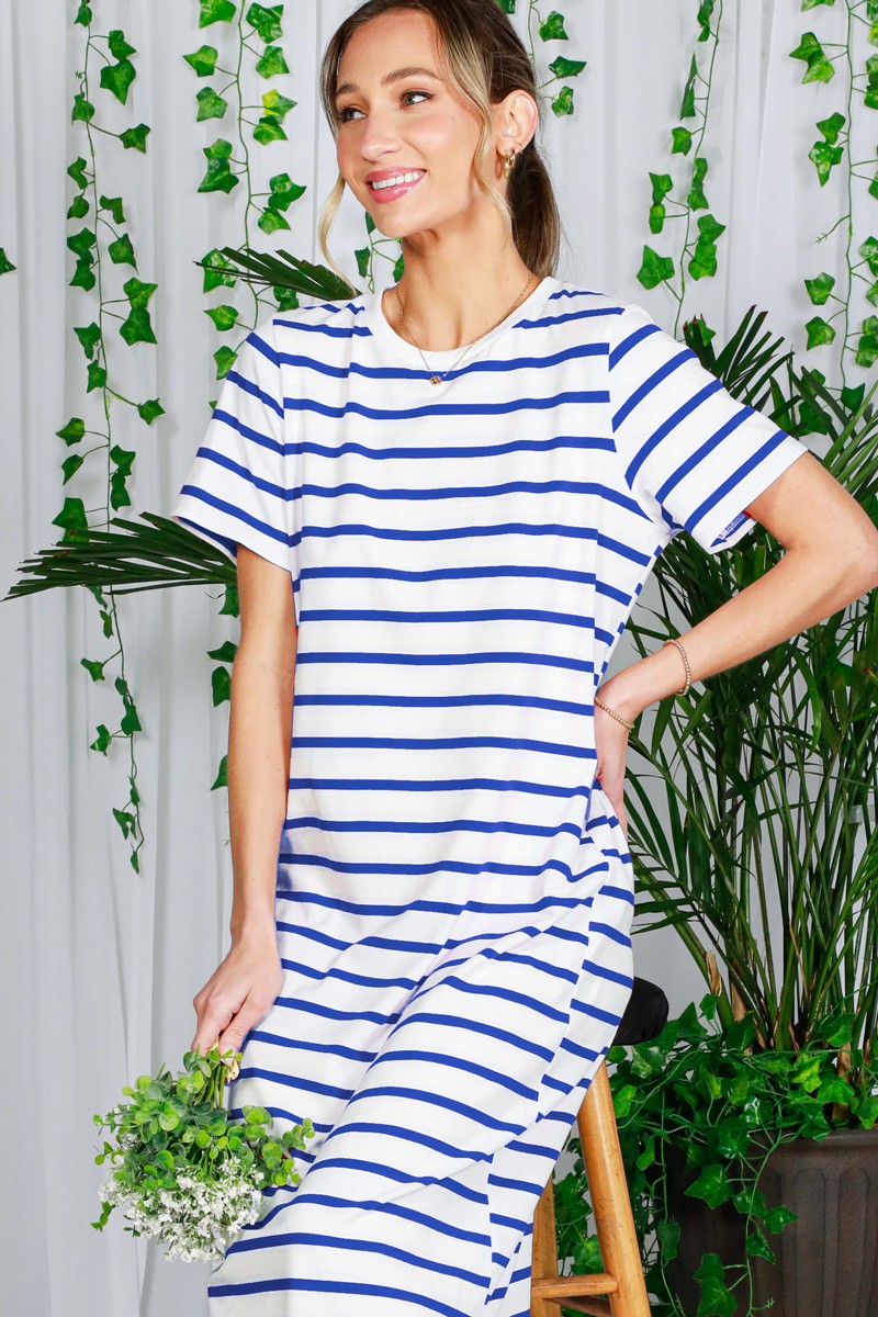 woman wearing a white and blue striped short sleeve dress while holding a small bouquet of flowers