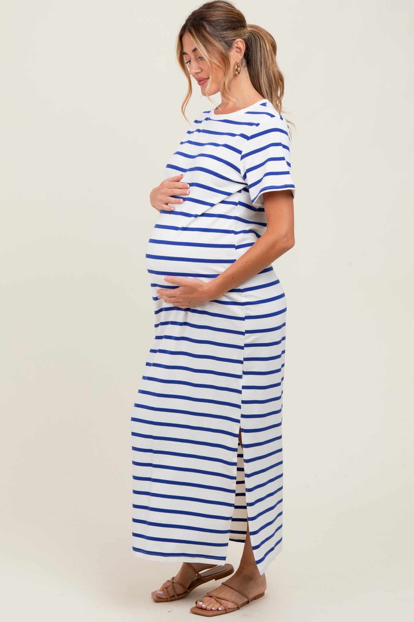 woman wearing a striped blue and white maternity dress with side slits and a visible baby bump