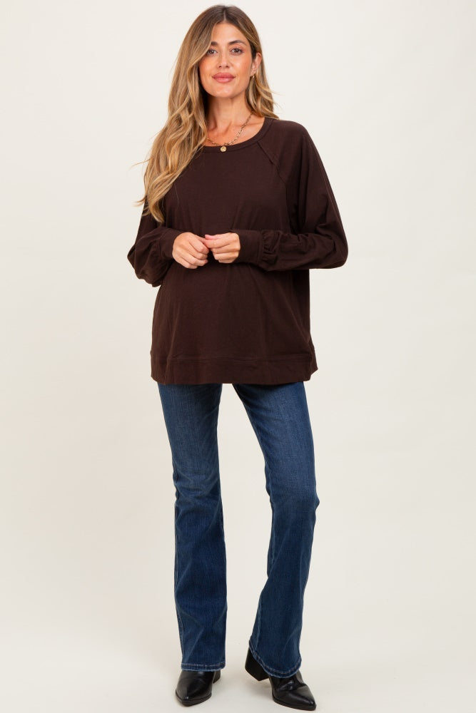 woman wearing a brown maternity sweatshirt with long sleeves and relaxed fit, paired with blue flared jeans