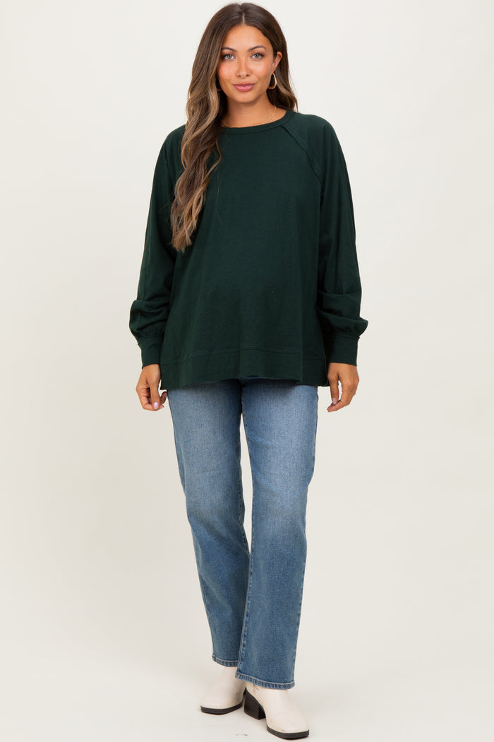 woman wearing a dark green maternity sweatshirt with raglan sleeves paired with light blue jeans