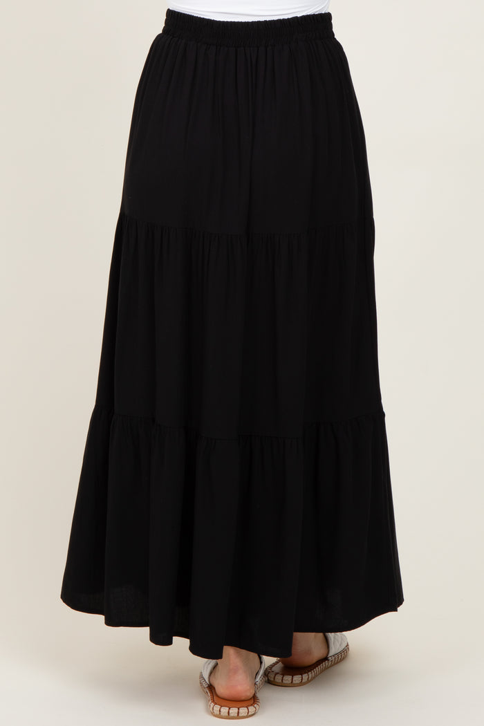 woman wearing a black tiered maxi skirt with an elastic waistband and flowy hemline