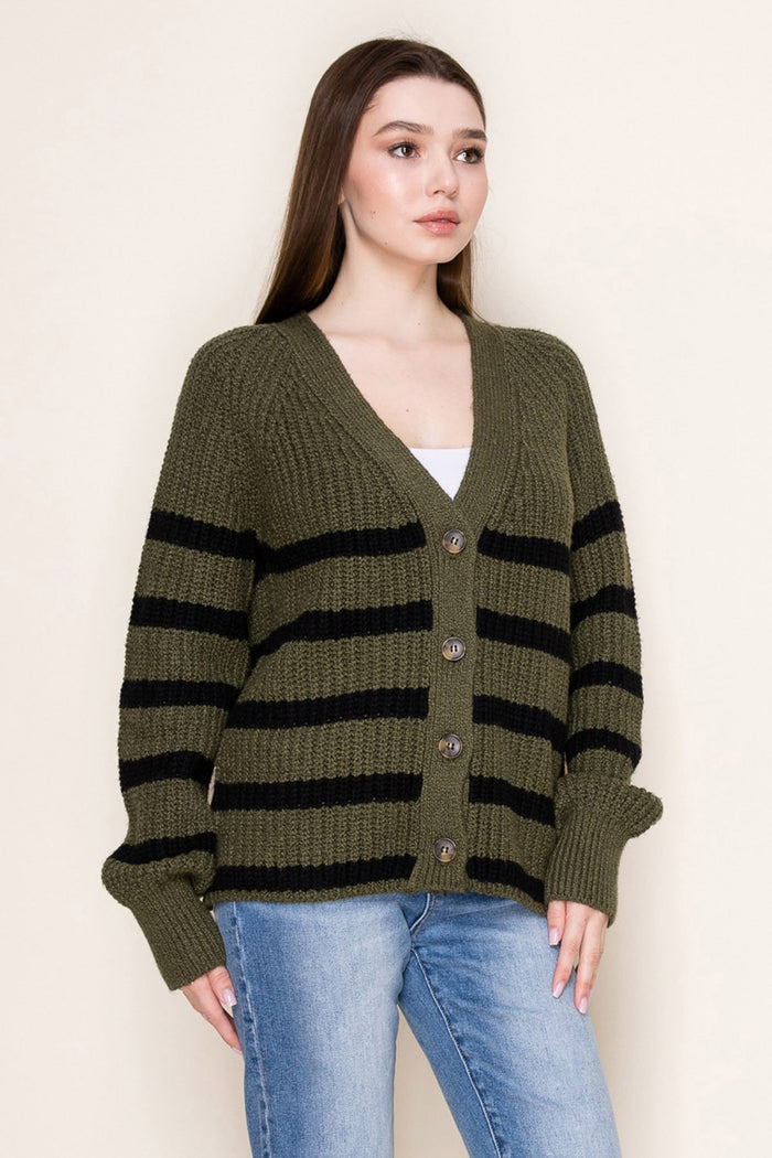 woman wearing an olive green and black striped cardigan with buttons and long sleeves, paired with light blue jeans