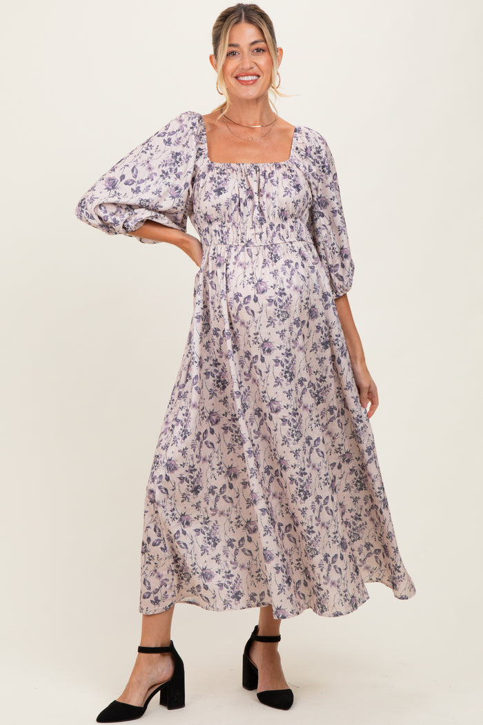 woman wearing a purple floral maxi maternity dress with puff sleeves and a visible baby bump