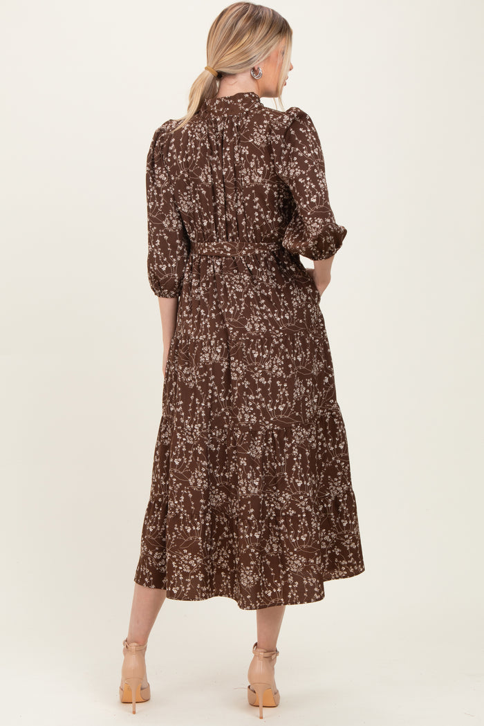 woman wearing a brown floral midi dress with puff sleeves and a tiered design, viewed from the back