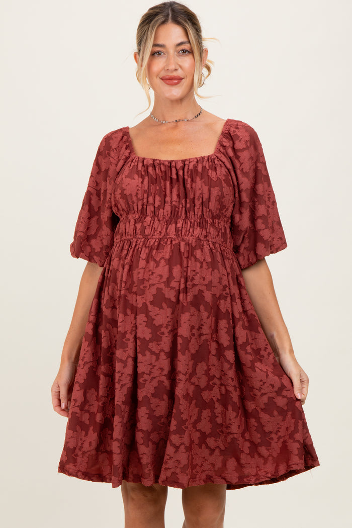 woman wearing a rust colored floral print maternity dress with square neckline and puff sleeves