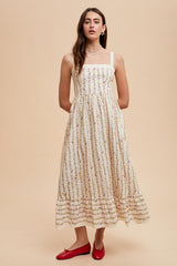 woman wearing a white floral midi dress with square neckline and spaghetti straps, standing in red flats