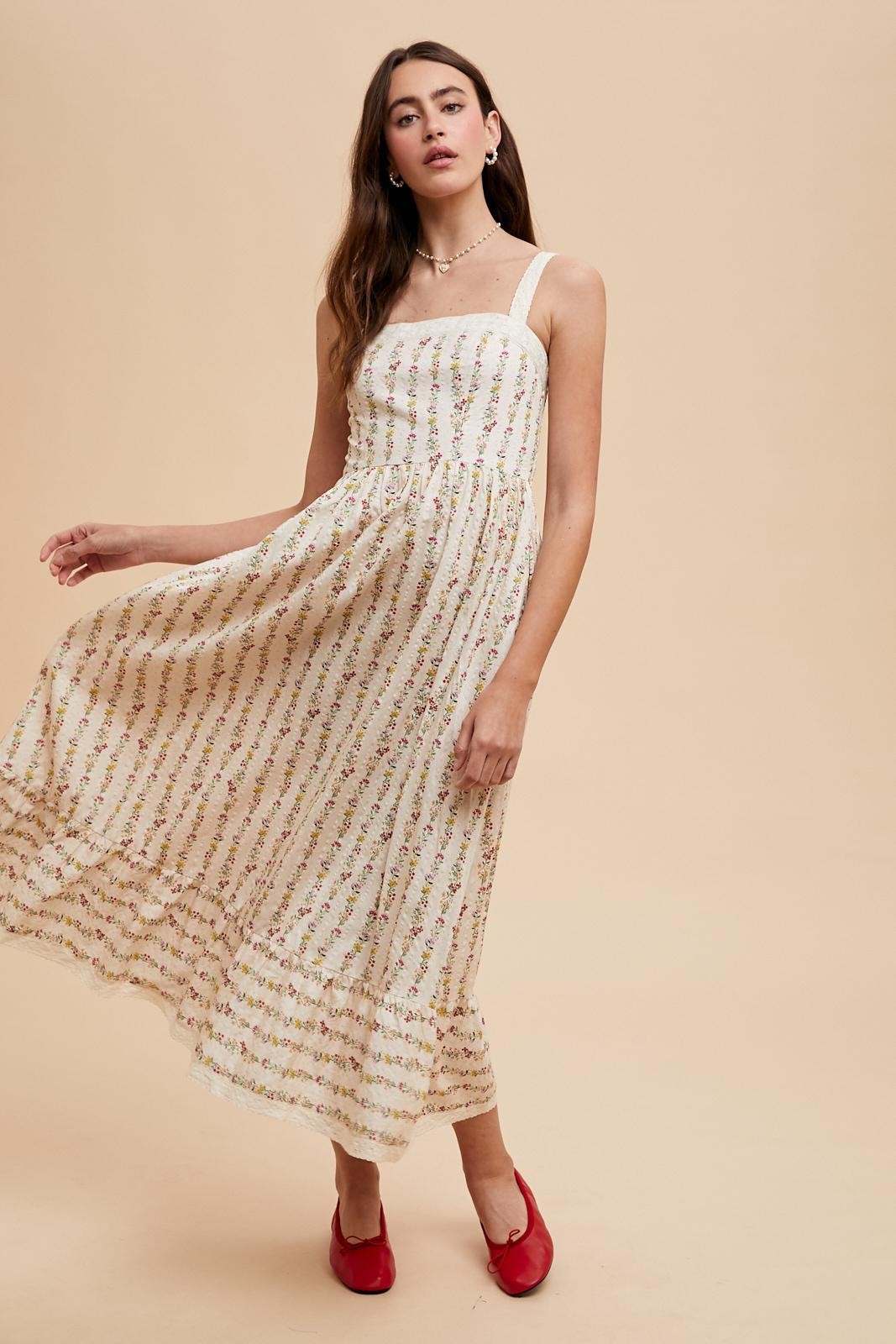 woman wearing a white floral midi dress with thin straps and ruffled hem, paired with red flats