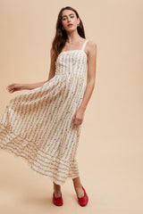 woman wearing a white floral midi dress with thin straps and ruffled hem, paired with red flats