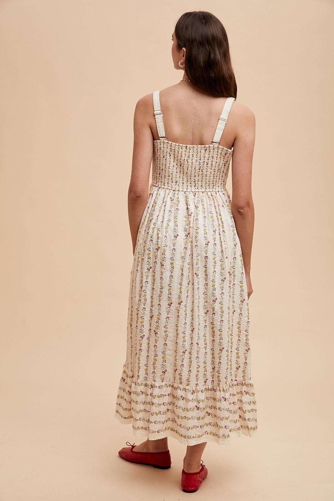 woman wearing a floral print midi dress with a smocked bodice and adjustable straps, showing the back view