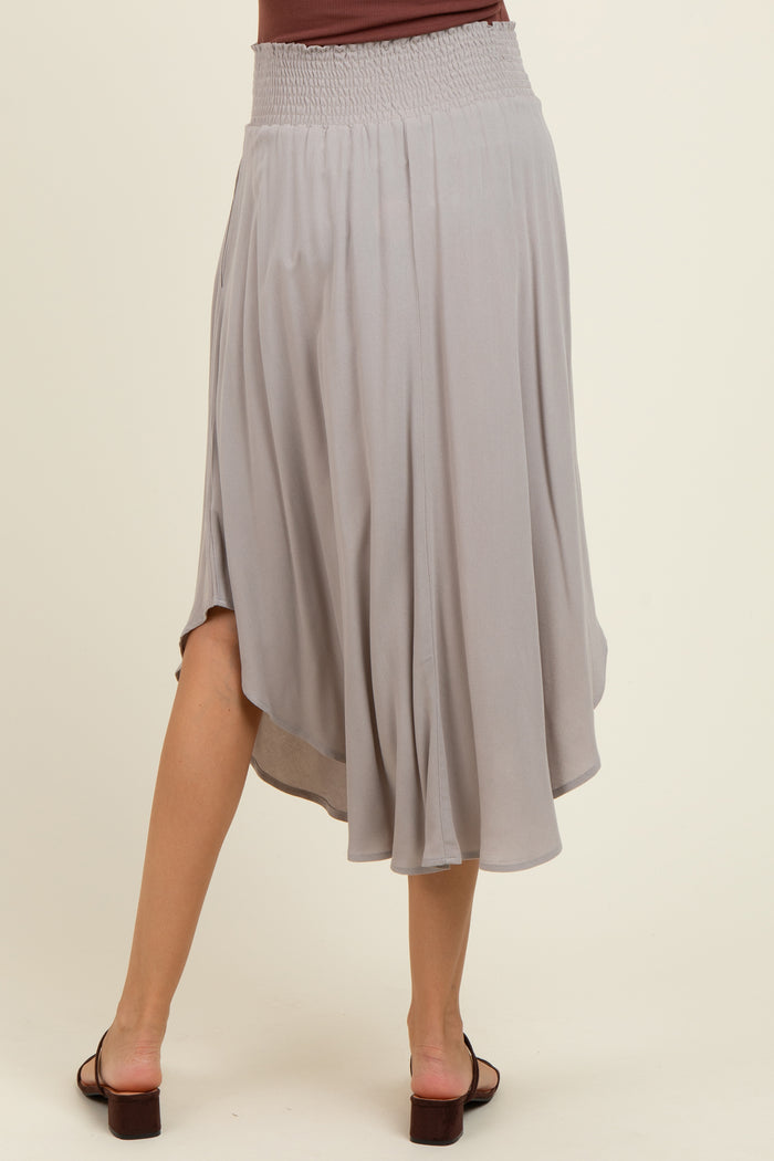 woman wearing a light gray maternity skirt with a smocked waist and flowing design, viewed from the back