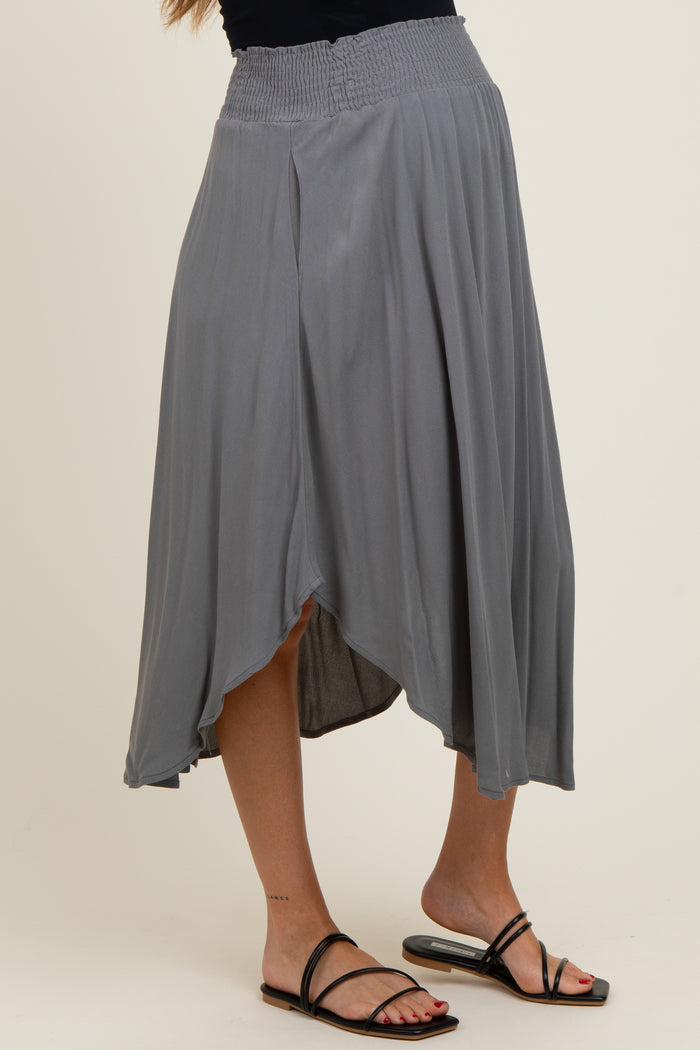 woman wearing a gray maternity skirt with a smocked waistband and asymmetrical hem, standing in a relaxed pose