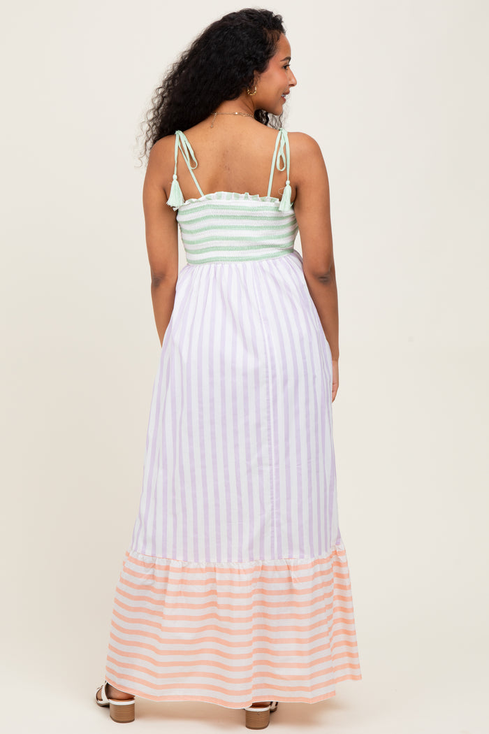 woman wearing a striped maternity maxi dress with a soft green smocked bodice and a flowy striped skirt