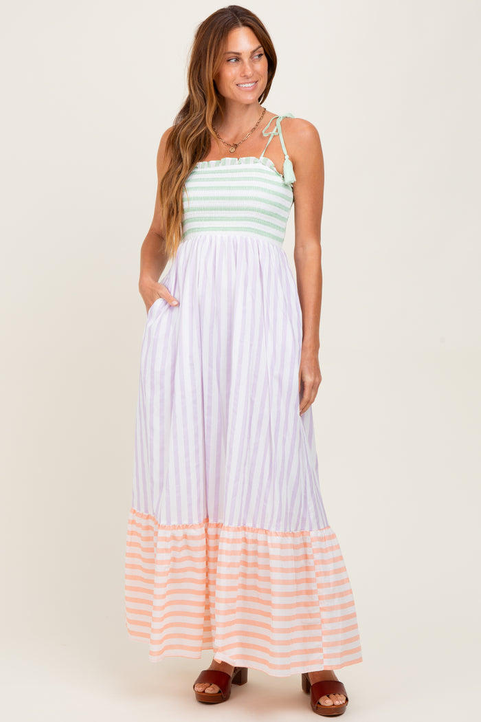 woman wearing a striped maxi dress with a smocked bodice and tiered skirt in pastel colors