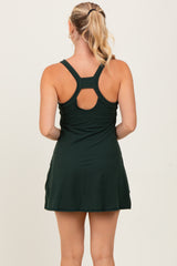 woman wearing a dark green sleeveless dress with a racerback and gathered detailing on the back