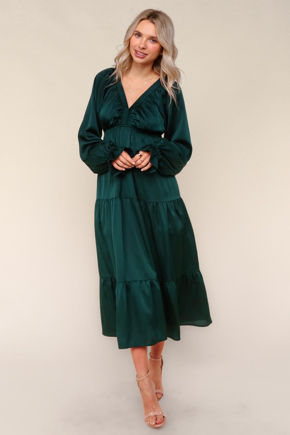 woman wearing a dark green long sleeve tiered maxi dress with a v-neckline and ruffled details