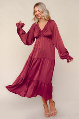 woman wearing a burgundy long sleeve maxi dress with a tiered skirt and puffed sleeves, smiling and in motion