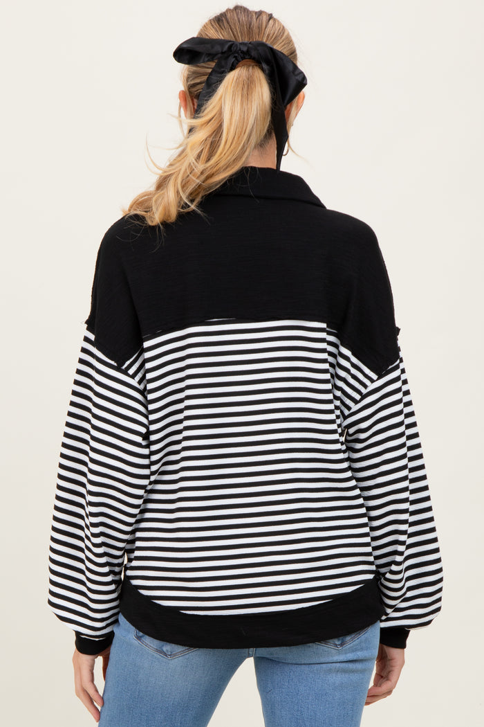 woman wearing a black and white striped maternity pullover with a collar and balloon sleeves, showing a baby bump