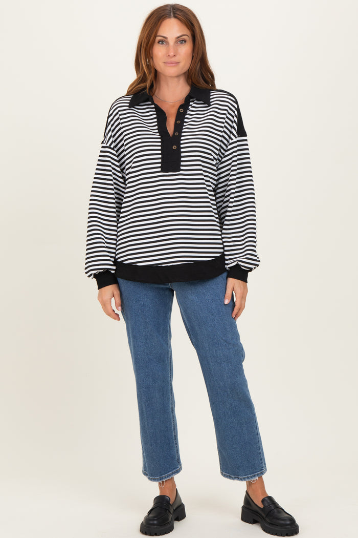 woman wearing a black and white striped pullover with a henley neckline and blue jeans