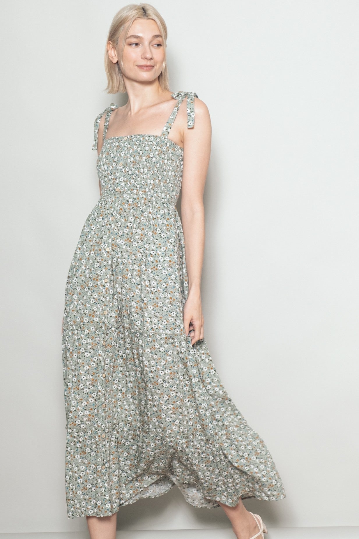 woman wearing a floral print maxi dress with adjustable tie straps and a smocked bodice