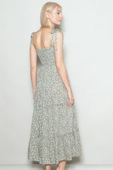 woman wearing a floral print maxi dress with tie straps, showing the back view and a fitted bodice