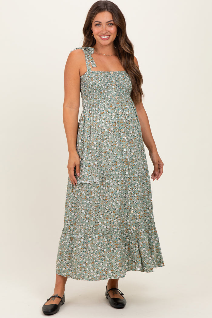 woman wearing a green floral maternity maxi dress with a square neckline and tie shoulder straps, showing her baby bump