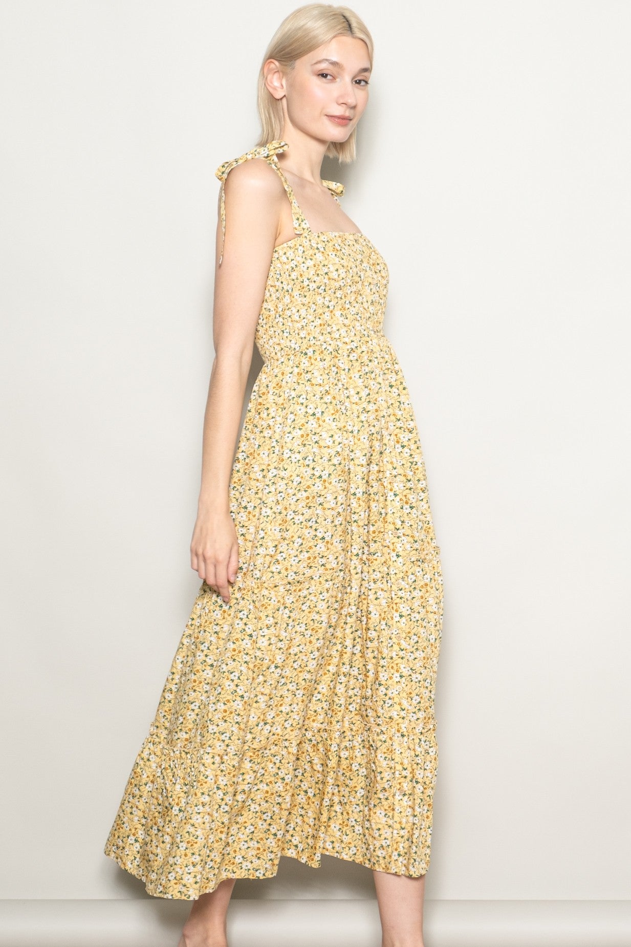 woman wearing a yellow floral maxi dress with tie shoulder straps