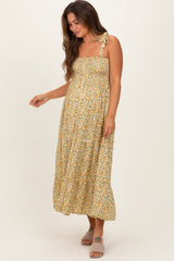 woman wearing a yellow floral maternity maxi dress with a smocked bodice and adjustable straps, showing her baby bump