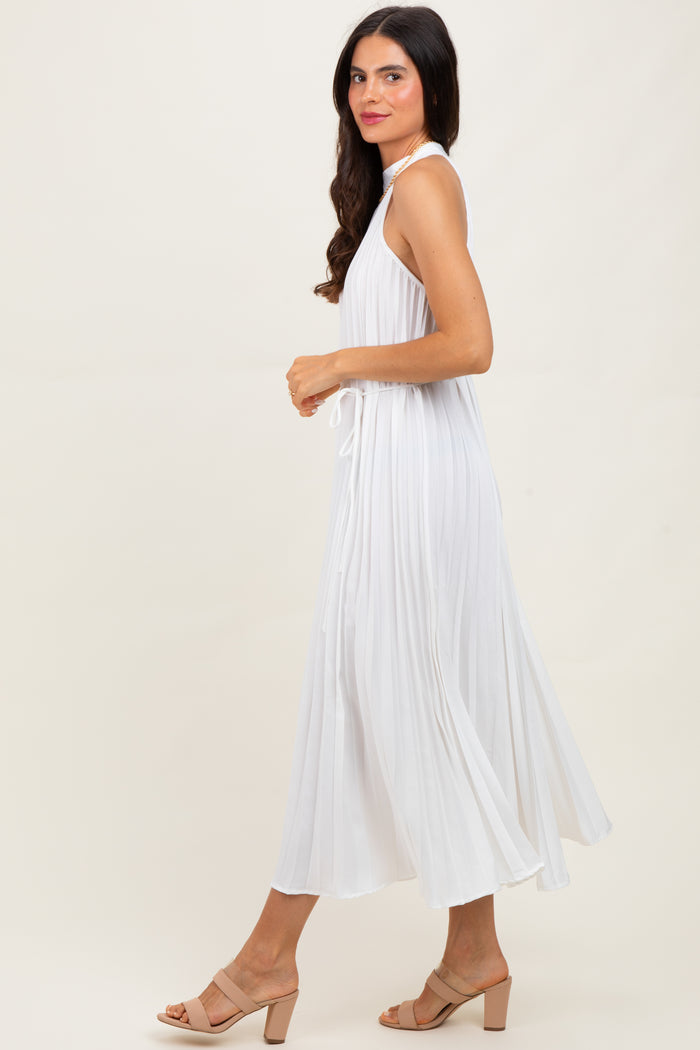 woman wearing a white sleeveless maxi dress with pleated details, styled with beige block-heel sandals