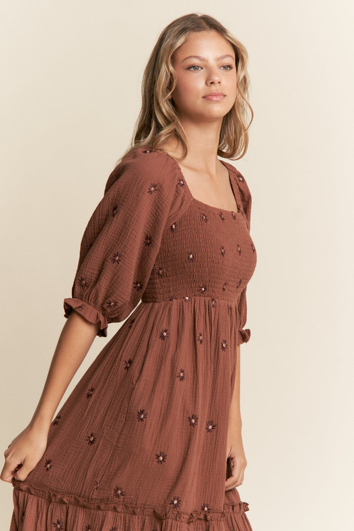 woman wearing a brown floral embroidered dress with a square neckline and puff sleeves