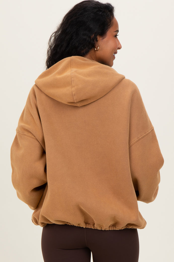 woman wearing a brown oversized hooded maternity sweatshirt with a cinched hem, showing her back