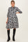 woman wearing a black and white floral maternity dress with three-quarter sleeves and knee-high black boots