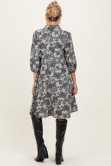 woman wearing a floral patterned maternity dress with three-quarter sleeves and a flowy silhouette, paired with knee-high black boots