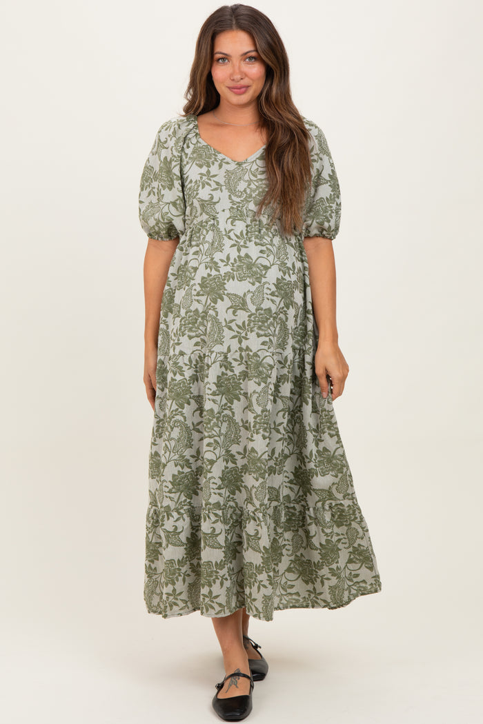 woman wearing a green floral print maternity maxi dress with puff sleeves and a v-neckline
