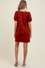 woman wearing a red maternity dress with puff sleeves and a striped collar, showing her back and legs