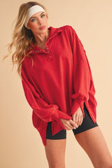 woman wearing a red oversized pullover with button details and black bike shorts, styled with a headband