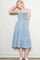 woman wearing a light blue tiered denim sundress with smocked bodice and tie straps