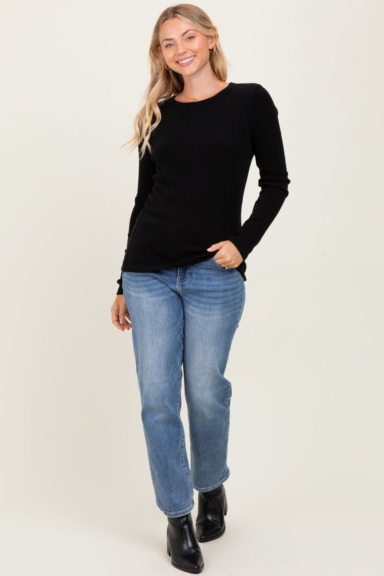 woman wearing a black ribbed long sleeve top and light blue straight leg jeans with black ankle boots